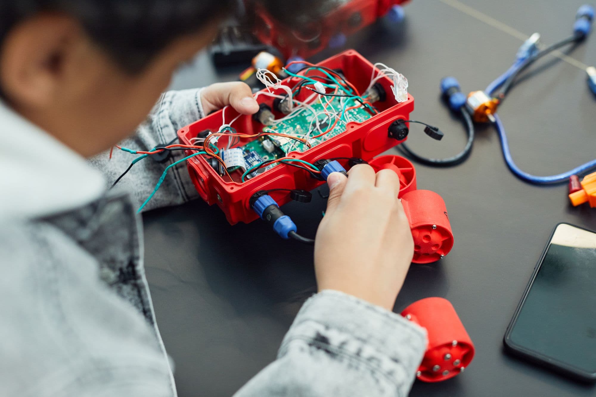 A child closely assembling a robot from electronic components